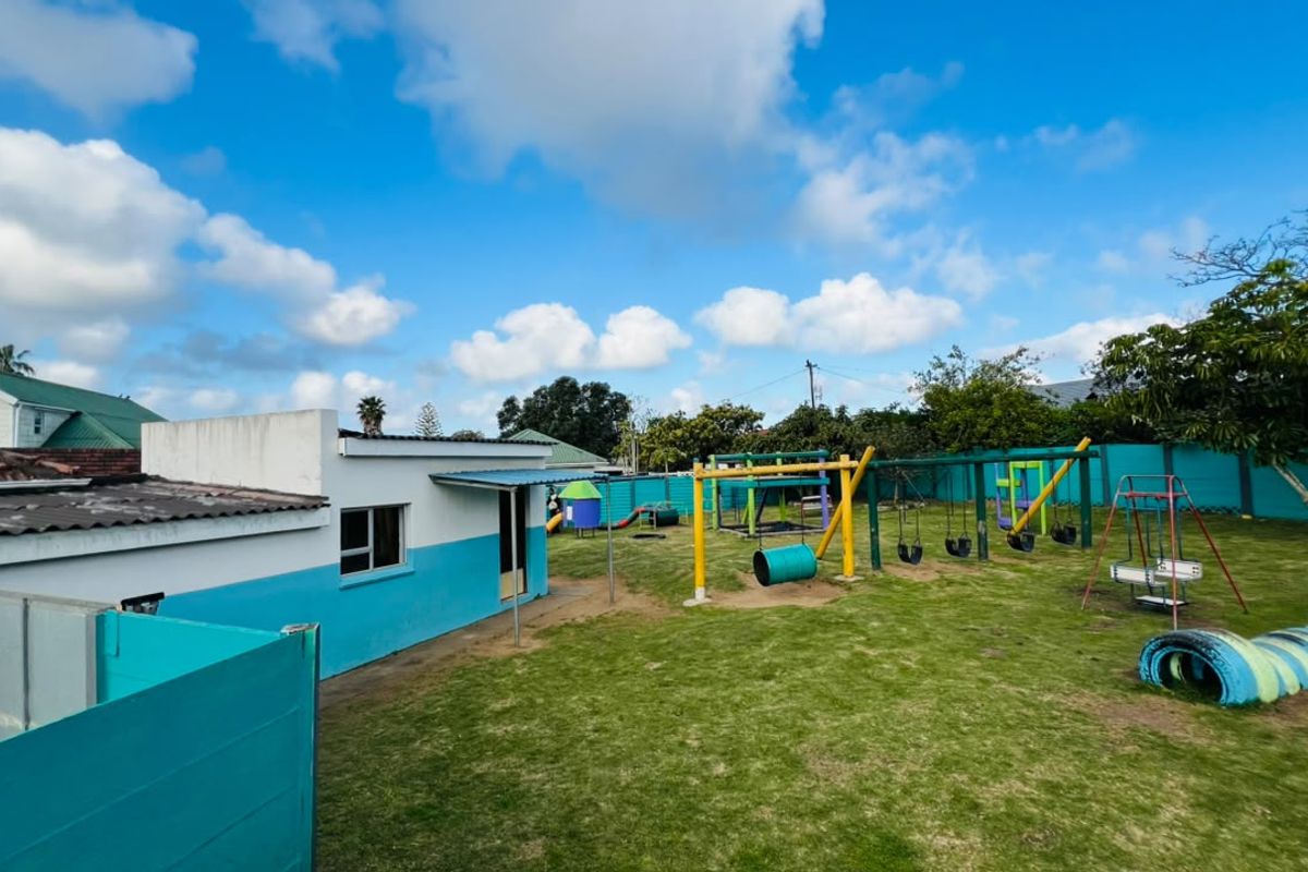A spacious rear garden area featuring a lawn and established playground equipment, enclosed by a boundary wall.