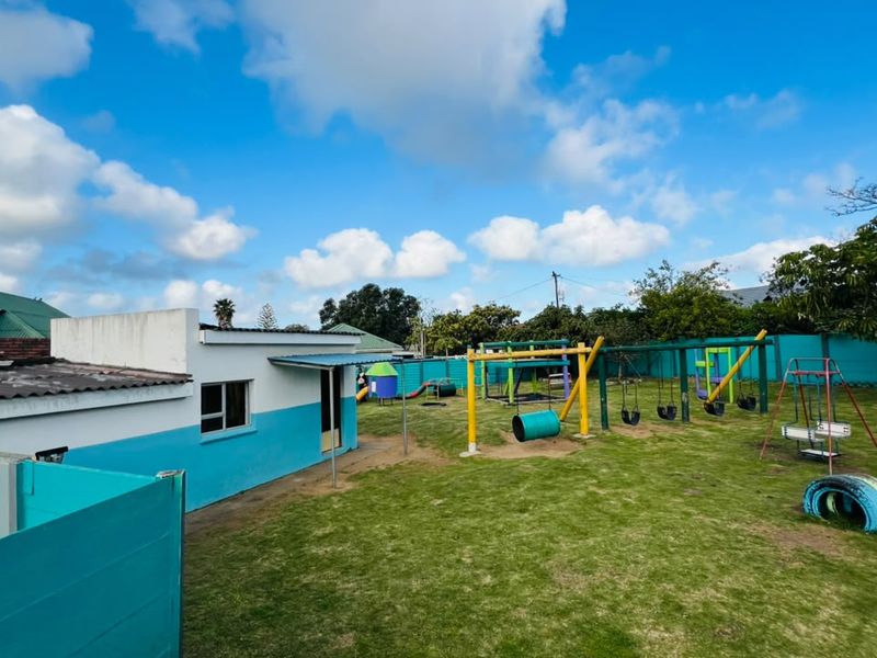 A spacious rear garden area featuring a lawn and established playground equipment, enclosed by a boundary wall.