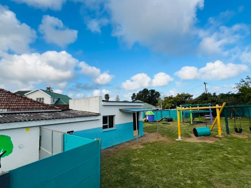 A spacious outdoor garden area featuring a playground with swings and a boundary wall, providing a functional recreational space.