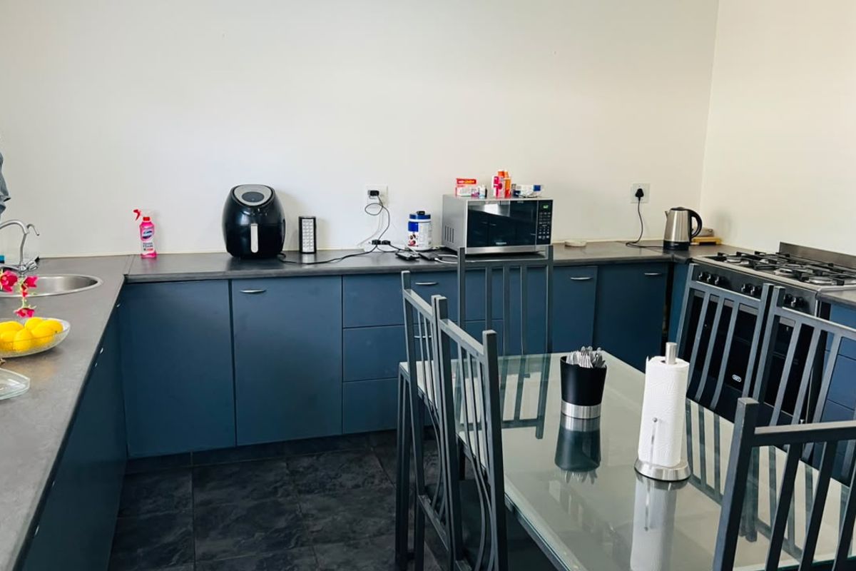 A functional kitchen featuring dark blue cabinetry, laminate countertops, a gas hob, and an integrated oven with dark tiled flooring.