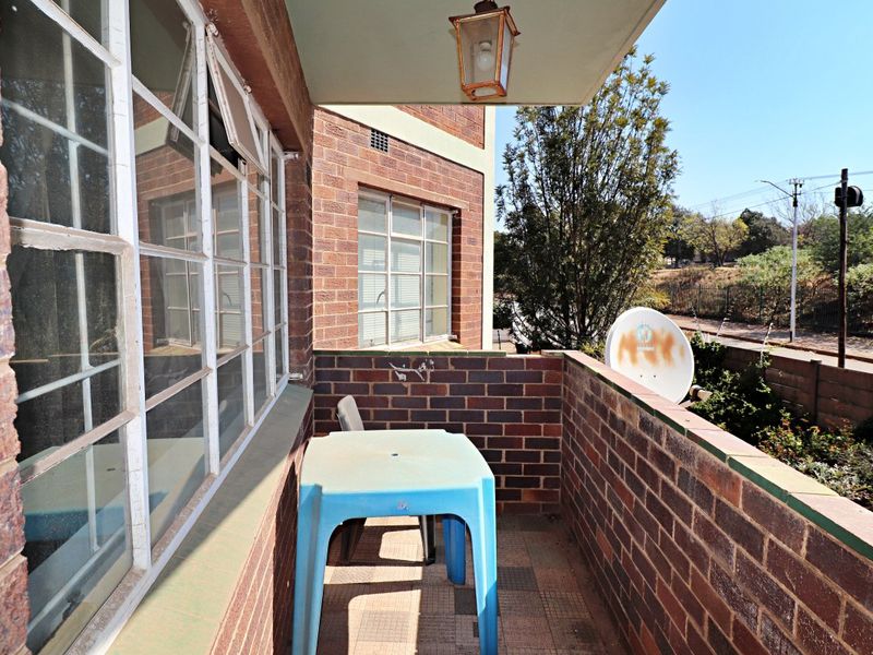 A functional balcony featuring brick walls, steel-framed windows, and tiled flooring, offering an outdoor space attached to the apartment.