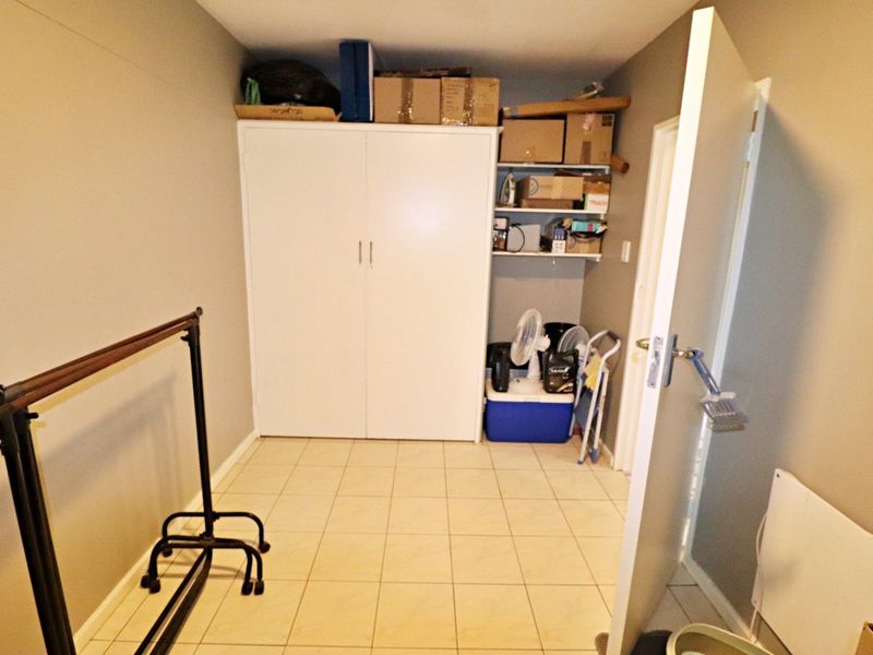 A utility room or storage area featuring tiled flooring, built-in cupboard storage, and open shelving.