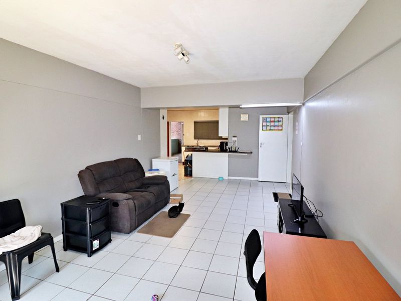 Open plan living area featuring tiled flooring and a functional kitchen space with built-in cabinetry and counter.