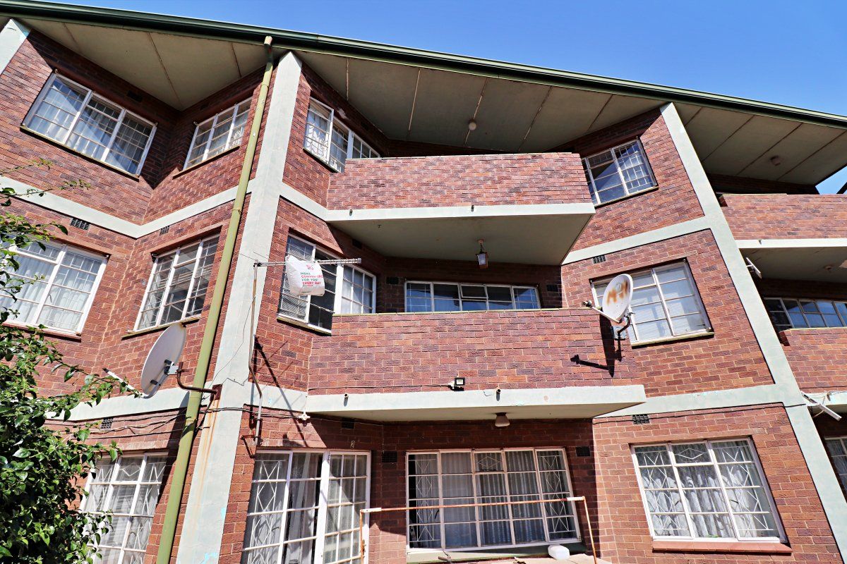 Rear elevation of a multi-story brick apartment building featuring private balconies and steel-framed windows.