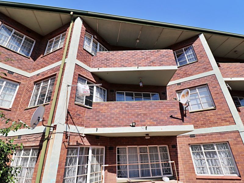 Rear elevation of a multi-story brick apartment building featuring private balconies and steel-framed windows.