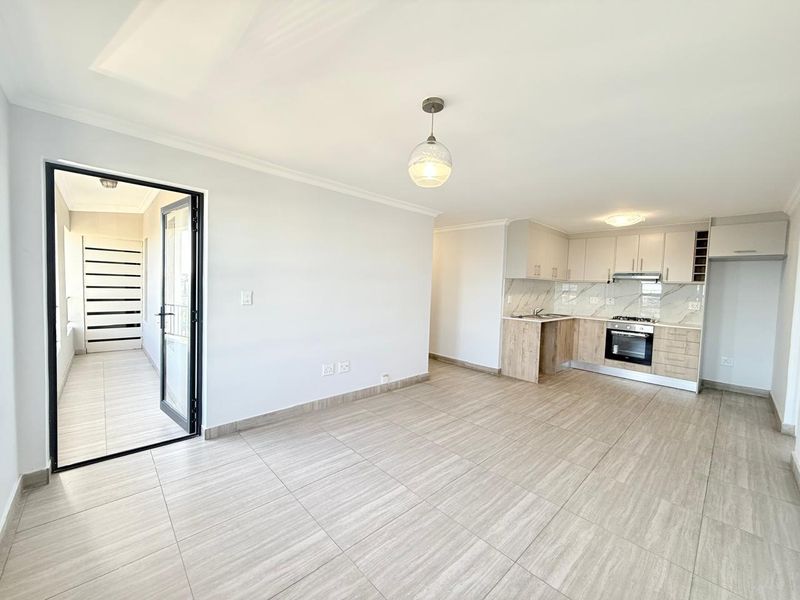 Modern open-plan living area featuring tiled floors, a contemporary kitchen with built-in appliances, and direct access to a private balcony.