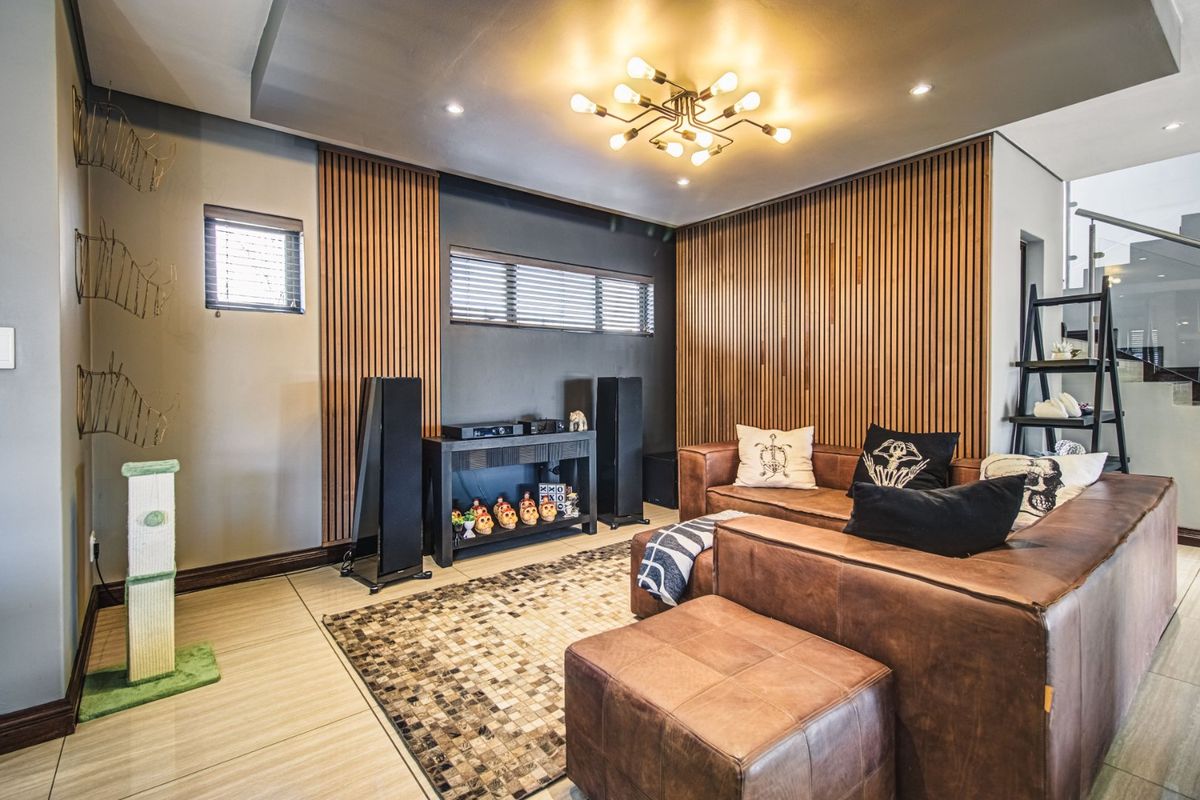 A modern living room featuring stylish timber slat wall paneling, contemporary ceiling lighting, and large format floor tiles.