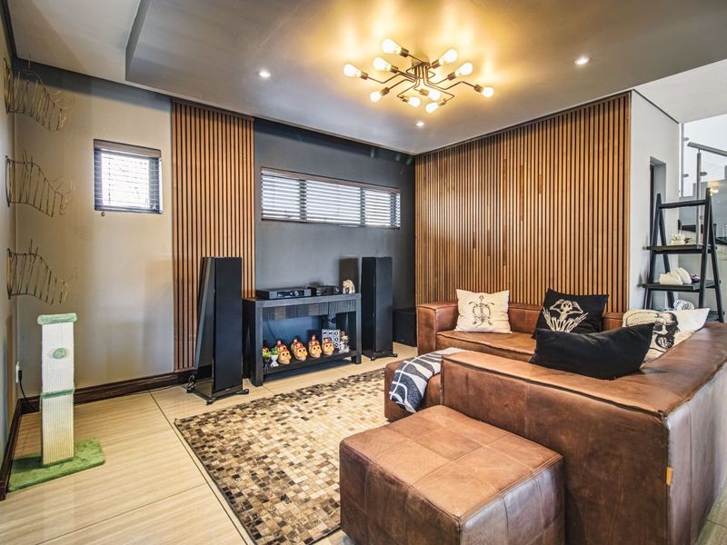 A modern living room featuring stylish timber slat wall paneling, contemporary ceiling lighting, and large format floor tiles.