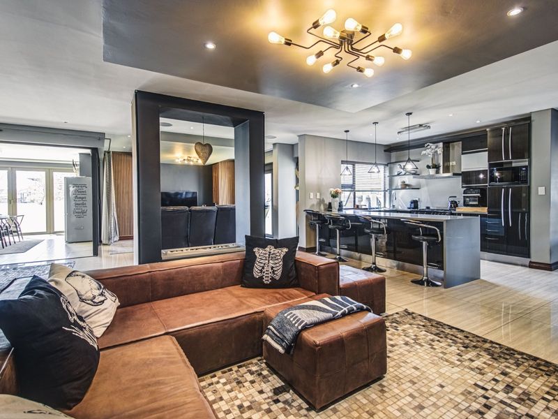 Modern open-plan living area featuring a sleek kitchen with a central island, high-end built-in appliances, and seamless flow to the adjacent dining space.