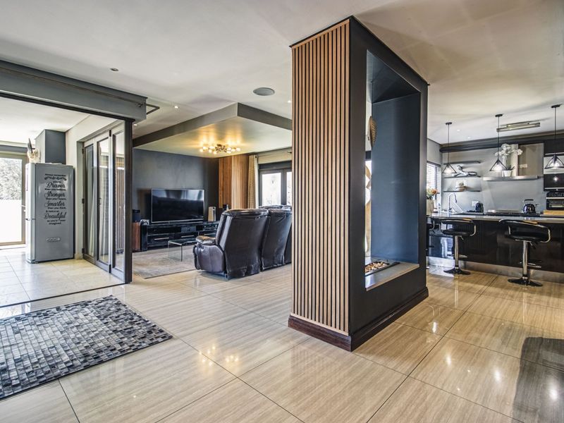 Modern open-plan living area featuring a striking slatted timber column, sleek tiled flooring, and a contemporary kitchen with integrated cabinetry and island.