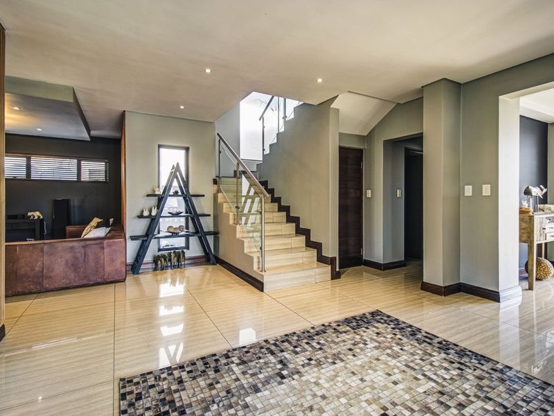 Spacious entrance hall featuring polished tiled flooring, a modern staircase with glass balustrades, and contemporary architectural detailing.