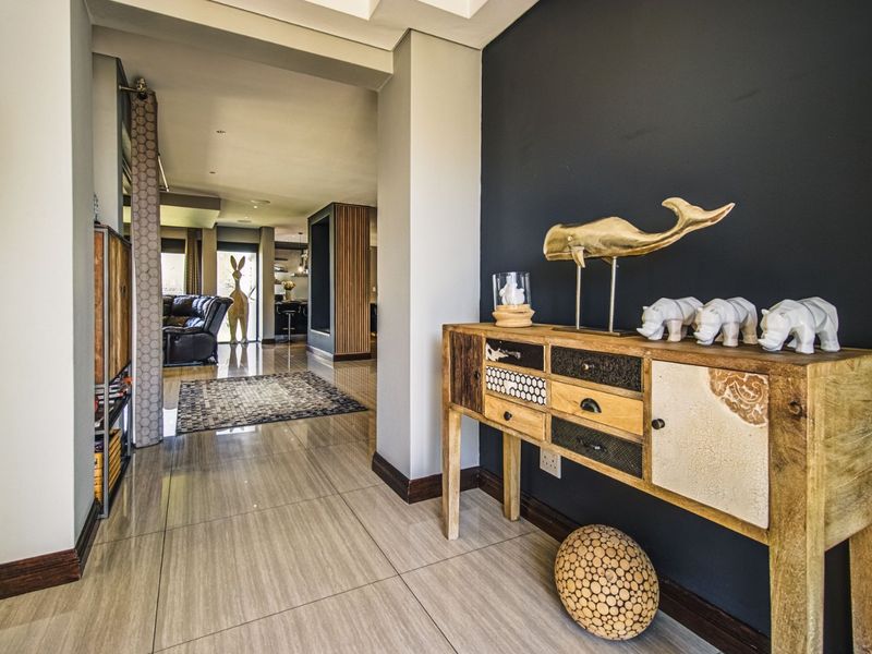 A welcoming entrance hall featuring polished tiled flooring and a modern dark accent wall, leading into the open-plan living area.
