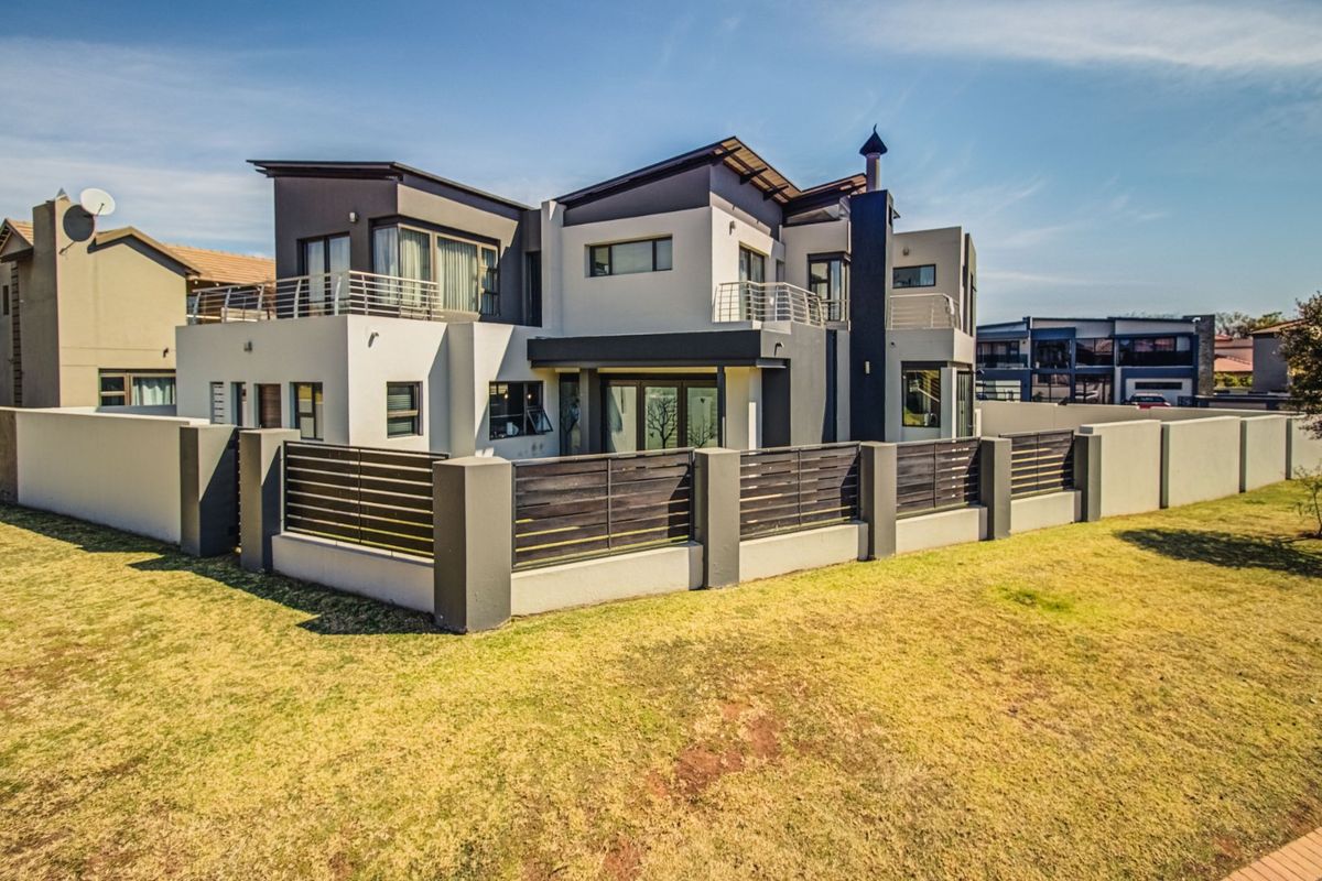 Modern double-story residence featuring contemporary architectural design, multiple balconies, secure boundary walling with timber fencing, and a well-maintained exterior facade.