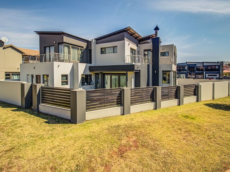 Modern double-story residence featuring contemporary architectural design, multiple balconies, secure boundary walling with timber fencing, and a well-maintained exterior facade.