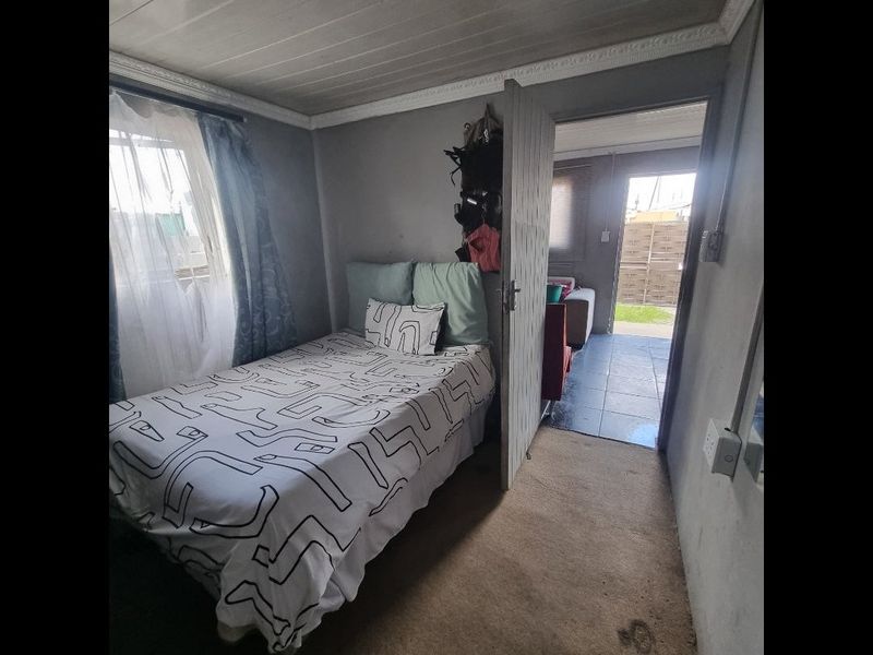 A compact bedroom featuring a timber ceiling and cornice, with an adjacent tiled area visible through the doorway.