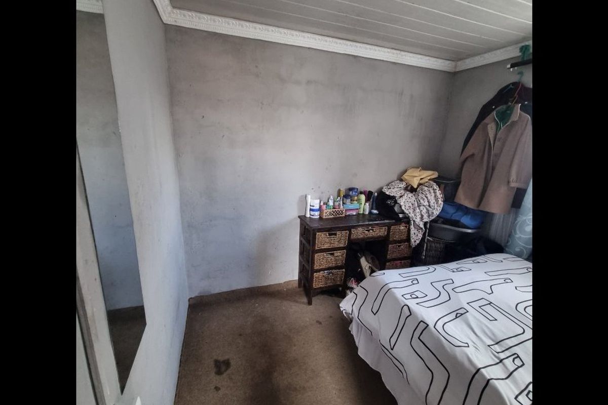 A bedroom featuring a tongue and groove ceiling with crown molding, requiring cosmetic updates to the walls and flooring.