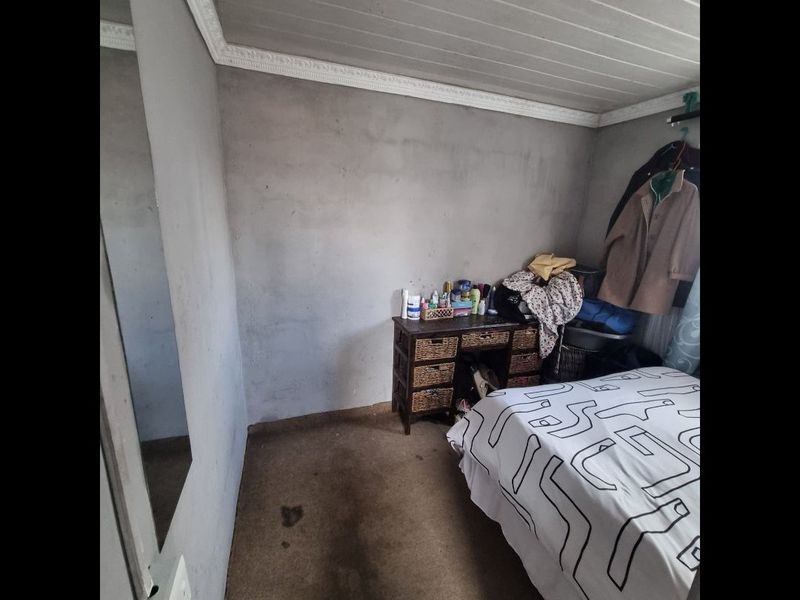 A bedroom featuring a tongue and groove ceiling with crown molding, requiring cosmetic updates to the walls and flooring.