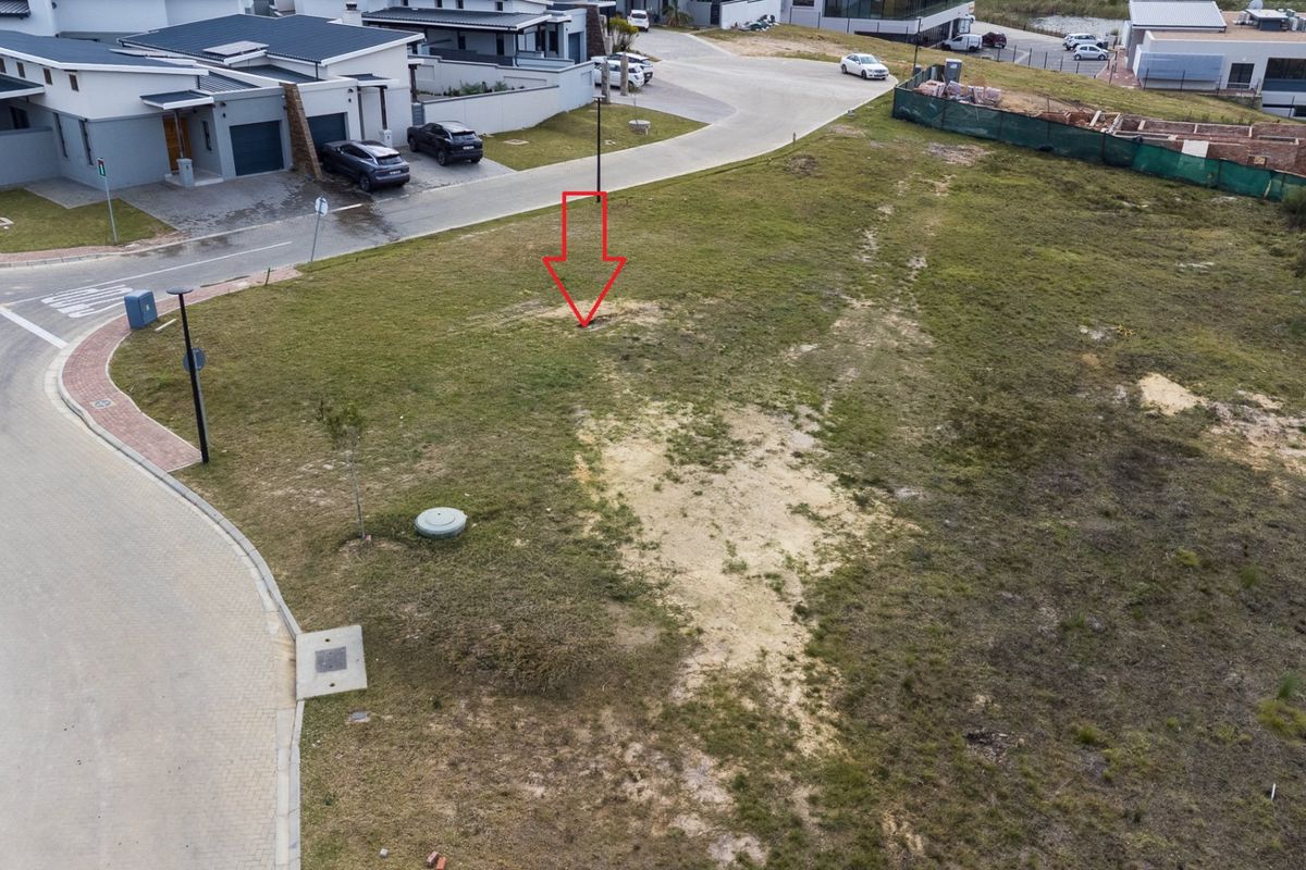 Aerial view of a vacant residential plot in a developed estate, featuring street access and utility infrastructure.