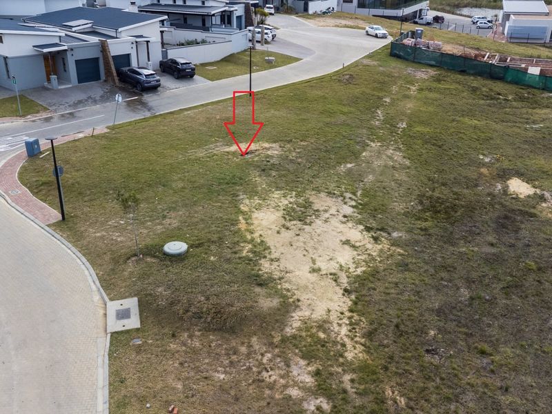 Aerial view of a vacant residential plot in a developed estate, featuring street access and utility infrastructure.