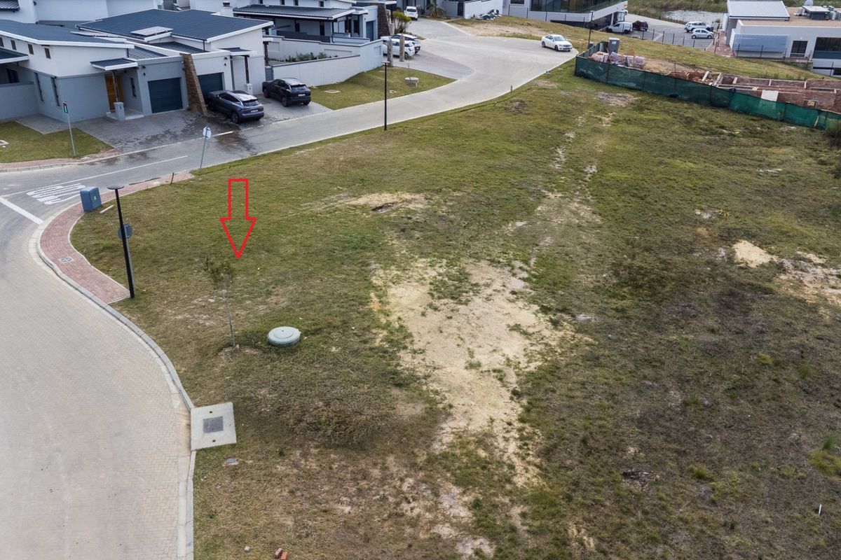 Aerial view of a vacant residential plot situated on a corner in a developed estate, featuring established road infrastructure and utility access points.