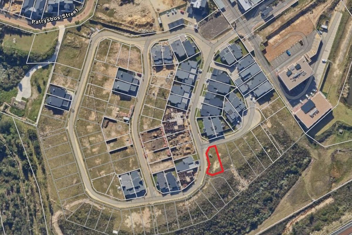 Aerial view of a vacant residential plot within a developed estate, highlighting its location, road access, and surrounding neighborhood context.