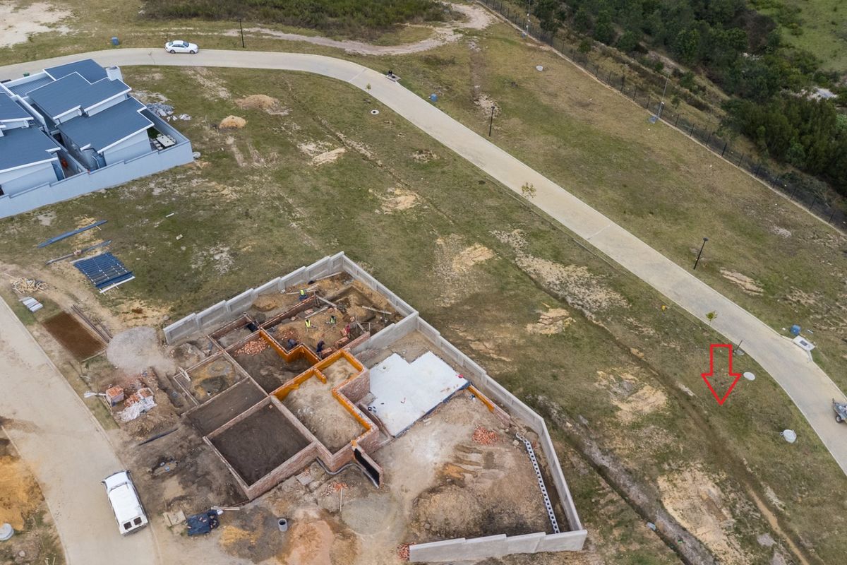 Aerial view of a residential property under construction, showing the foundation, brickwork, and concrete slab on a vacant plot.