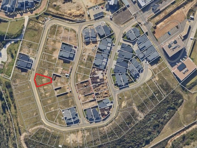 Aerial view of a vacant residential plot within a developed estate, highlighting the site boundaries and surrounding infrastructure.