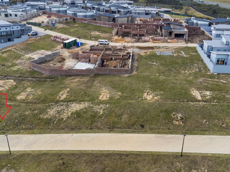 Aerial view of a vacant residential plot in a developing estate, featuring access to paved roads and established utility infrastructure.