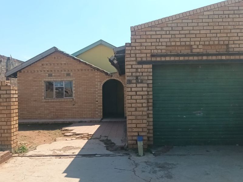Front elevation of a face brick house featuring a roller shutter garage door and a paved entrance walkway.