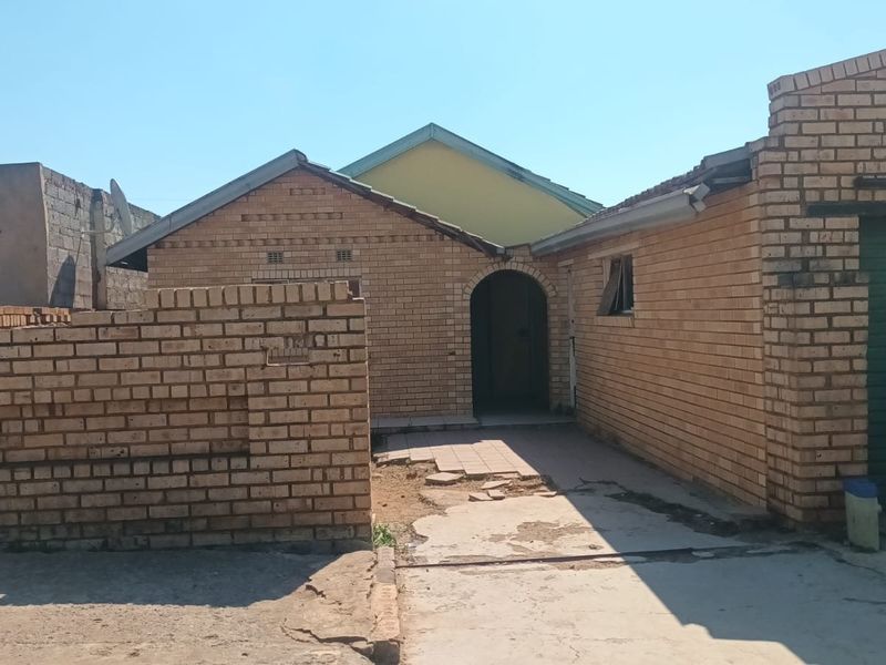 Front elevation of a face brick house featuring an arched entrance, concrete driveway, and attached garage structure.