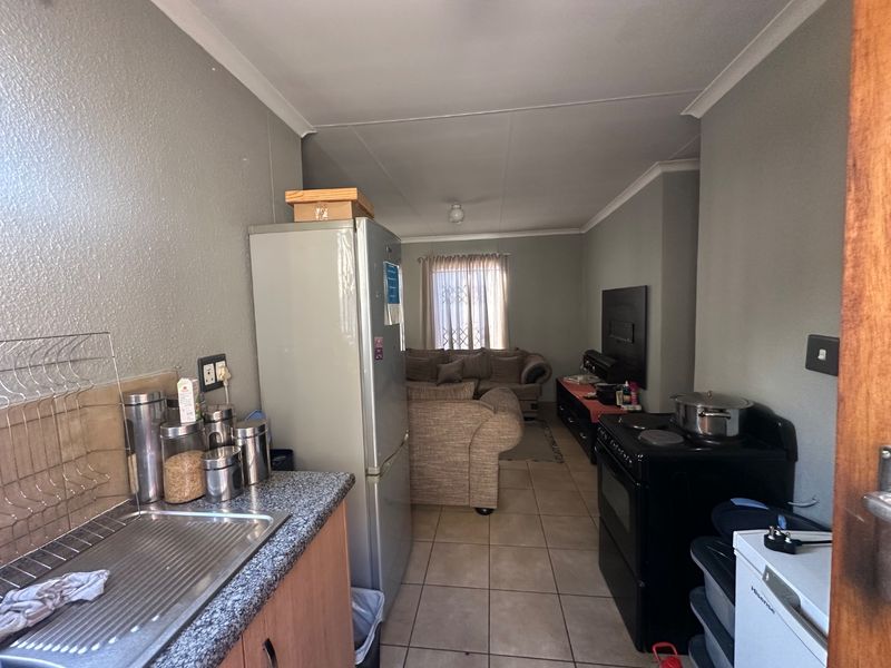 Open-plan living area featuring a functional kitchen space with tiled flooring and direct flow into the adjacent lounge area.