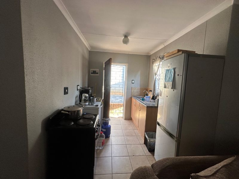 A functional kitchen featuring tiled flooring, built-in cabinetry, and direct access to the exterior through a rear door.