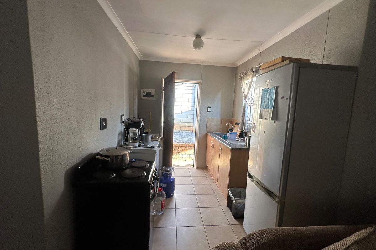 A functional galley-style kitchen featuring tiled flooring, built-in cabinetry, and direct access to an outdoor area.