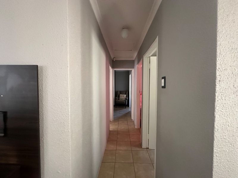 A functional hallway featuring tiled flooring and neutral wall finishes, providing access to multiple rooms within the home.