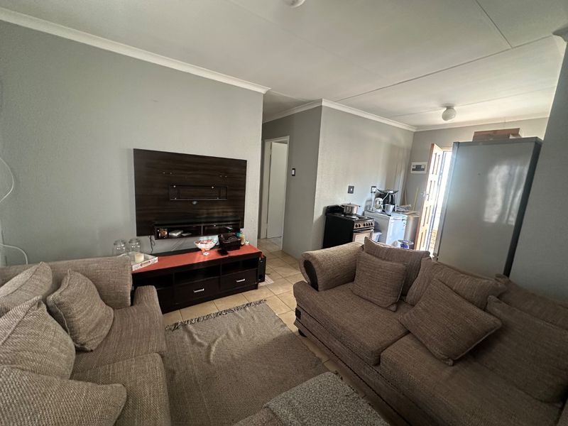 Open plan living area featuring tiled flooring and coved ceilings, seamlessly connecting to a functional kitchen space.