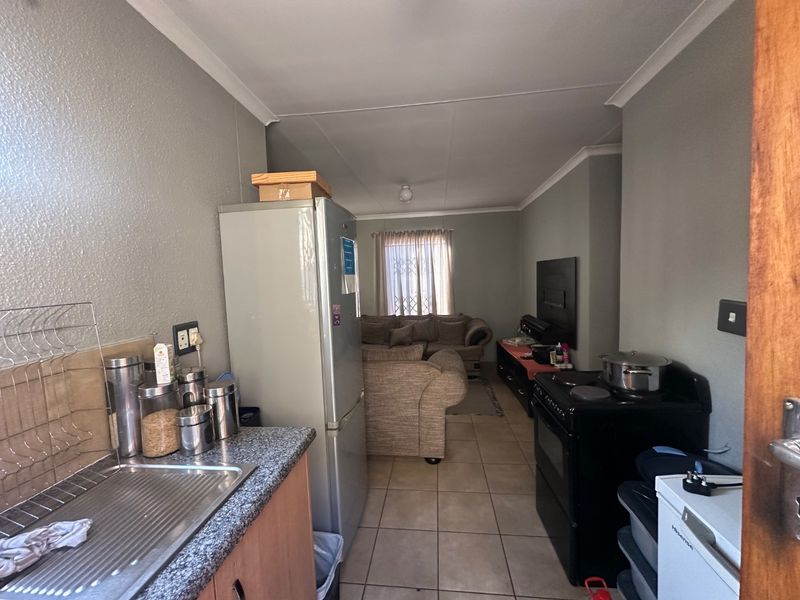 Open-plan kitchen and living area featuring tiled flooring, laminate countertops, and a functional layout connecting the cooking space to the lounge.