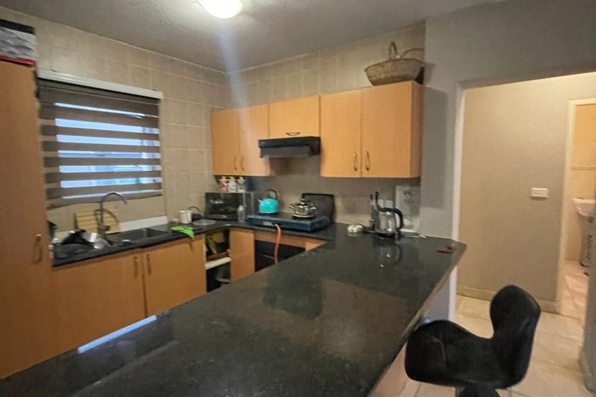 A functional kitchen featuring granite countertops, laminate cabinetry, and a tiled backsplash, offering a practical layout with an integrated breakfast bar.