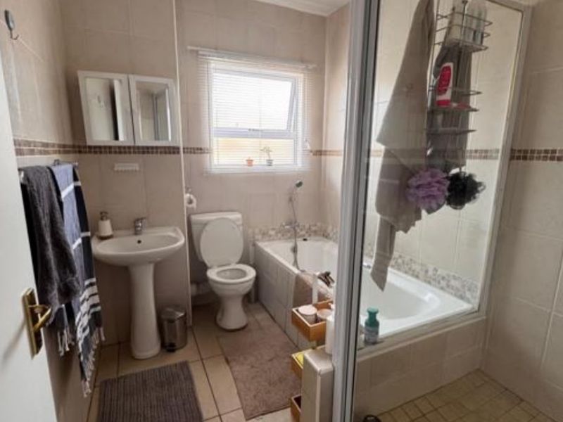 A functional bathroom featuring a pedestal basin, toilet, bathtub, and a separate shower enclosure with tiled finishes throughout.