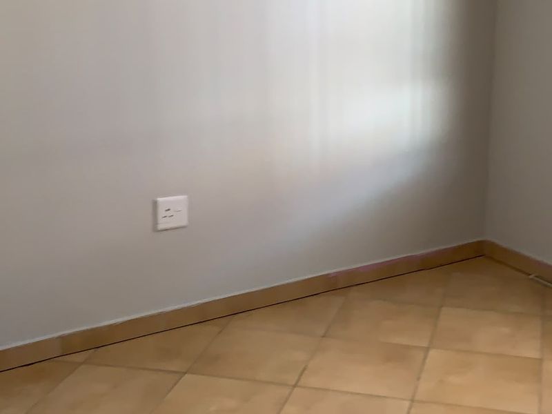 An empty room featuring neutral wall paint, ceramic tile flooring, and standard skirting boards.