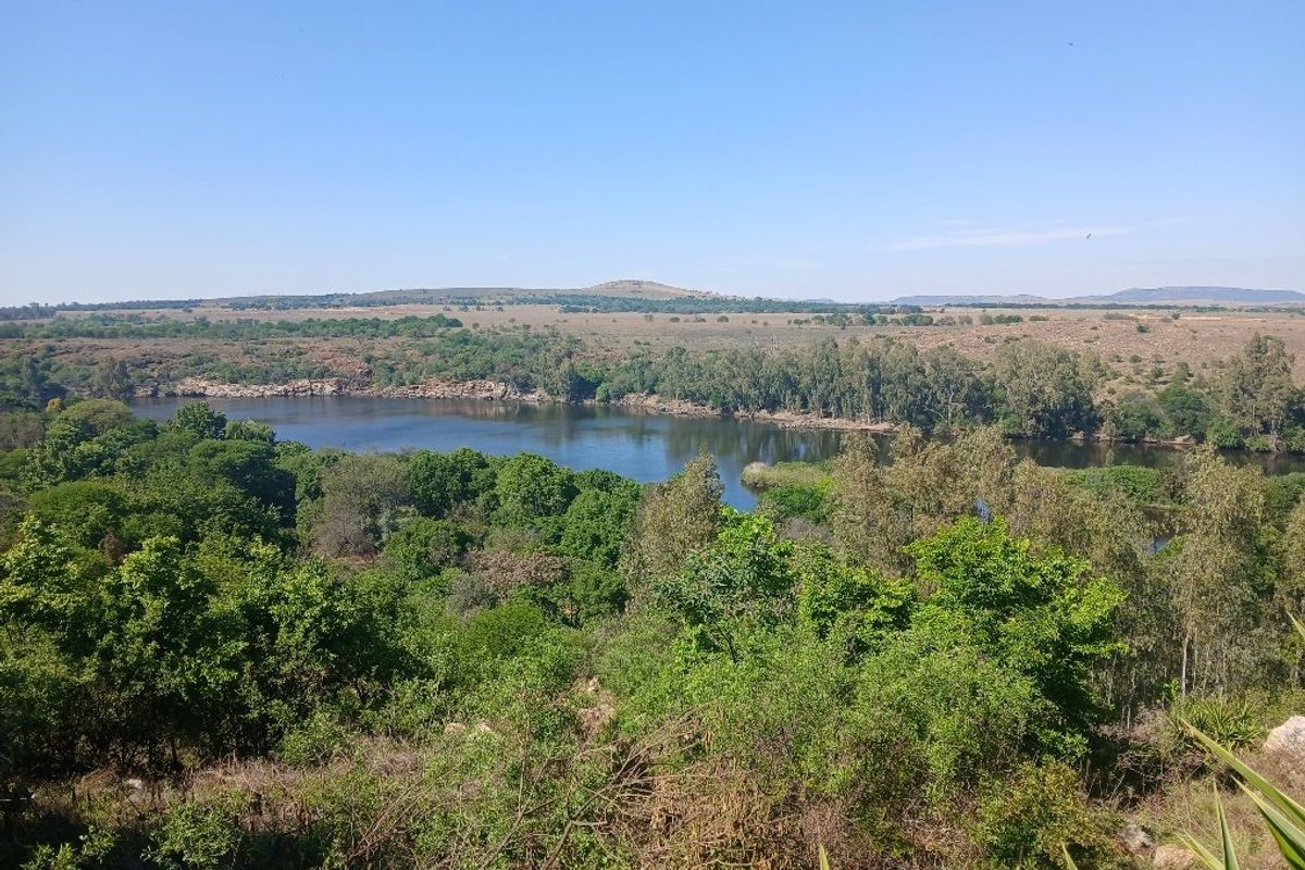 A scenic elevated view overlooking a natural river and surrounding lush landscape, showcasing the tranquil environment of the vacant land.