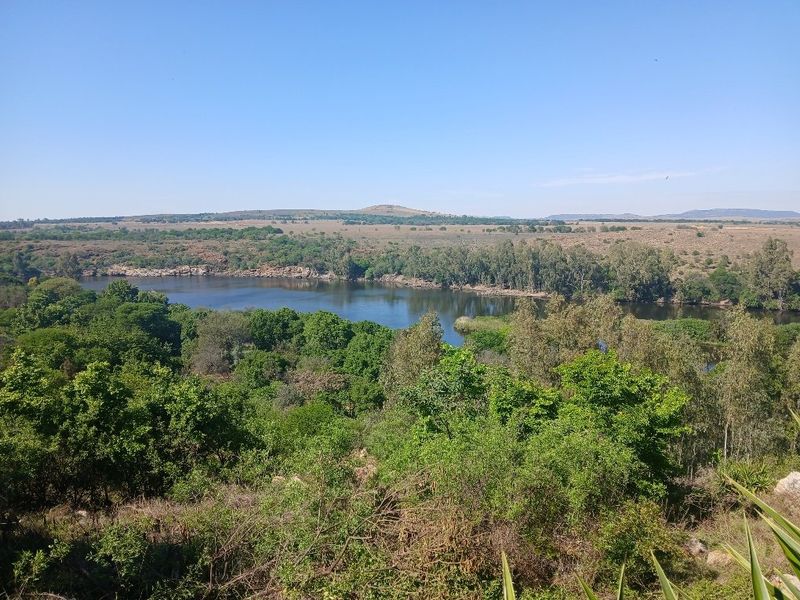 A scenic elevated view overlooking a natural river and surrounding lush landscape, showcasing the tranquil environment of the vacant land.