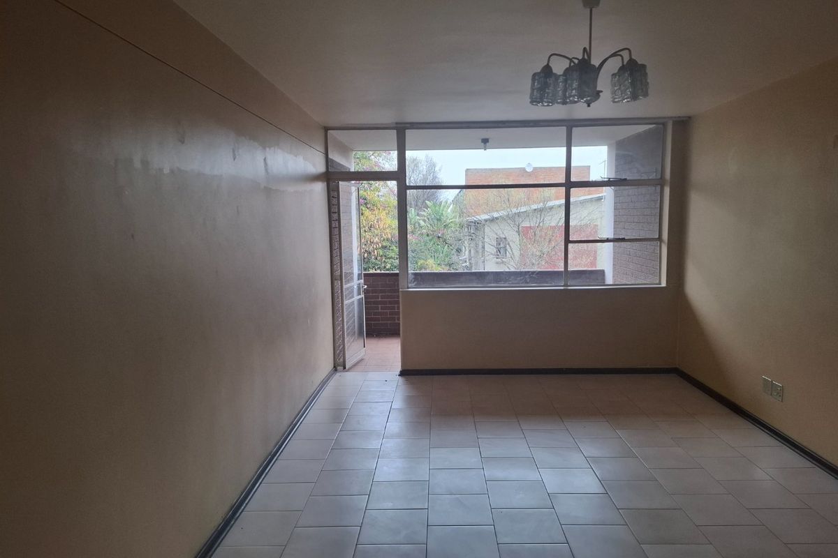 An empty living room featuring tiled flooring, a large window, and access to an outdoor balcony area.