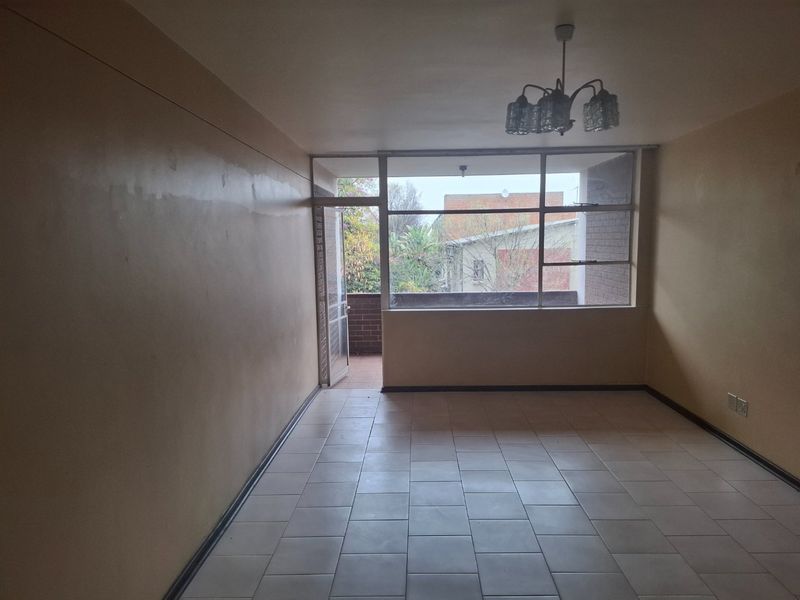 An empty living room featuring tiled flooring, a large window, and access to an outdoor balcony area.