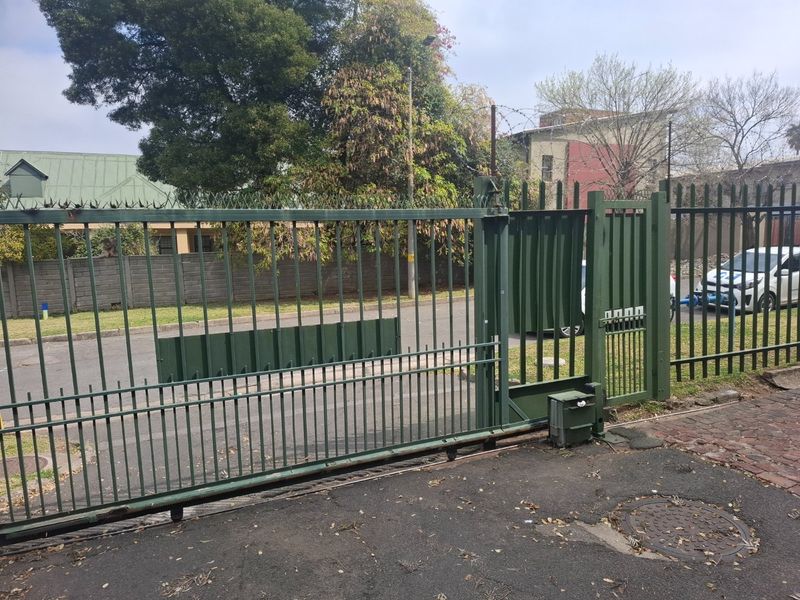 Front entrance featuring a sliding security gate with an electric motor and steel palisade fencing topped with razor wire.