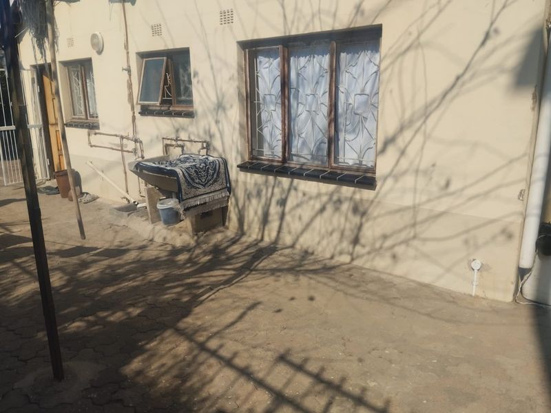 Rear exterior view of the property featuring a paved courtyard, utility sink, and security-fitted windows.