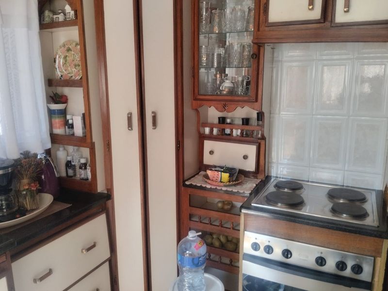A dated kitchen featuring traditional wooden cabinetry, built-in electric stove, and tiled splashback, offering potential for a modern renovation.