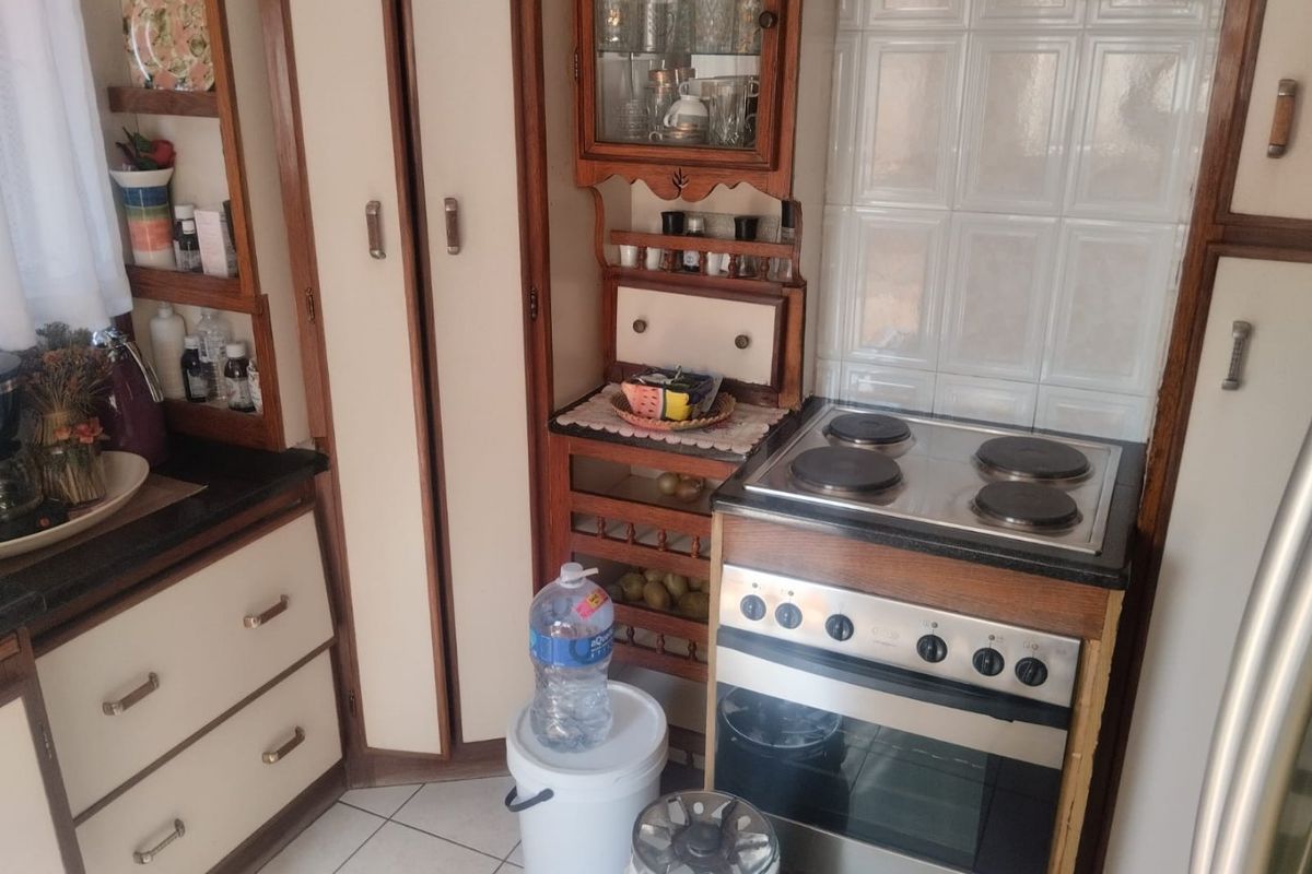 A compact kitchen featuring dated wooden cabinetry, a built-in electric stove and oven, and tiled backsplash.