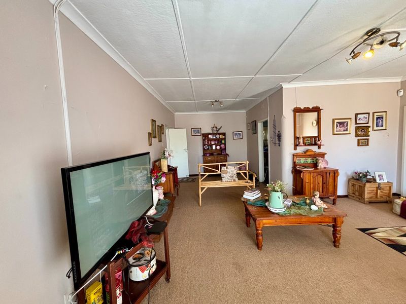 Spacious living room featuring carpeted flooring, coved ceilings with tile panels, and visible surface-mounted electrical conduit along the wall.