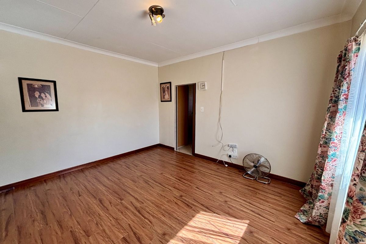 A vacant bedroom featuring laminate flooring, coved ceilings, and neutral wall finishes, ready for personalization.