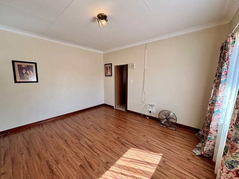 A vacant bedroom featuring laminate flooring, coved ceilings, and neutral wall finishes, ready for personalization.